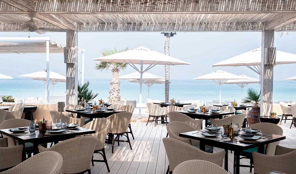 Restaurante con vistas a la playa y sombrillas blancas 