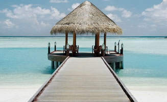 Imagen de pasarela de madera en hotel lujo Maldivas con mar y cielo de fondo. 