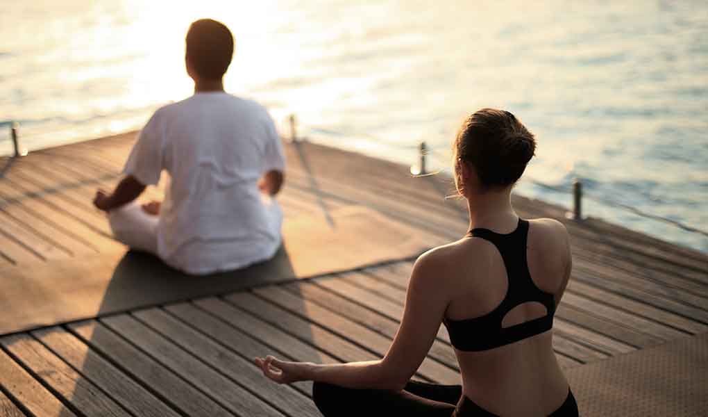 Dos personas en una clase se yoga en Maldivas hotel Baros Maldives