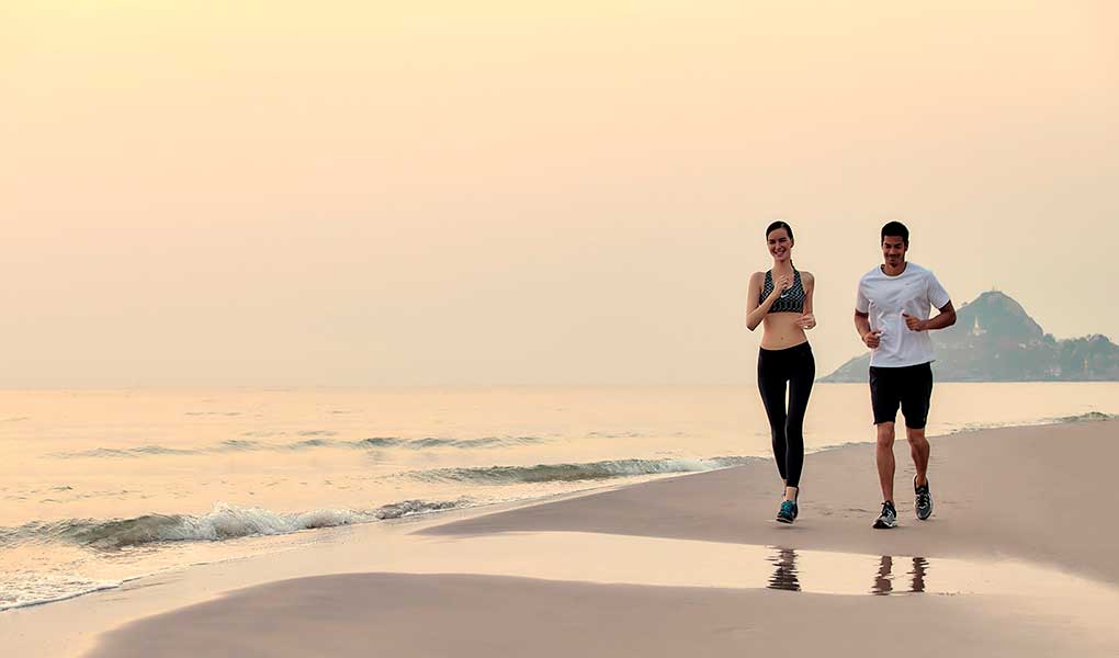 Pareja haciendo ejercicio corriendo en la playa en Tailandia