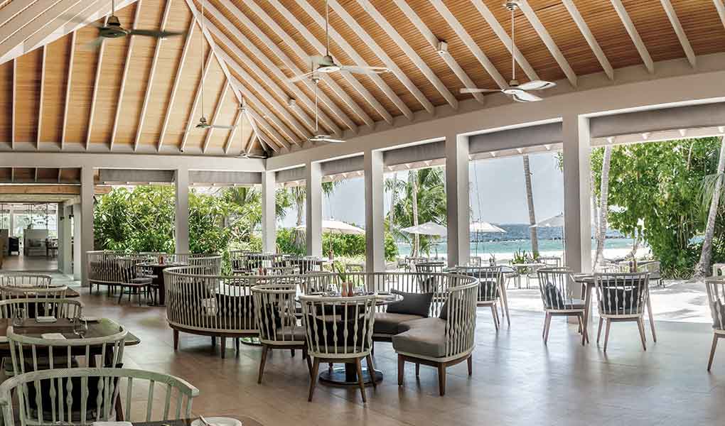 Restaurante exterior del hotel con detalles en madera y vistas a la playa
