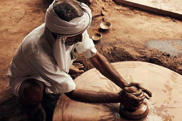 Artesano en India realizando trabajo en barro con las manos
