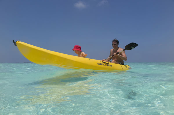 Padre e hijo pequeño piragua amarilla en mar en Maldivas viajes familia en hotel Anantara Dhigu