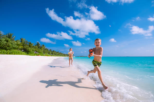 Niños corriendo playa en Maldivas hotel Ozen Life Maadhoo