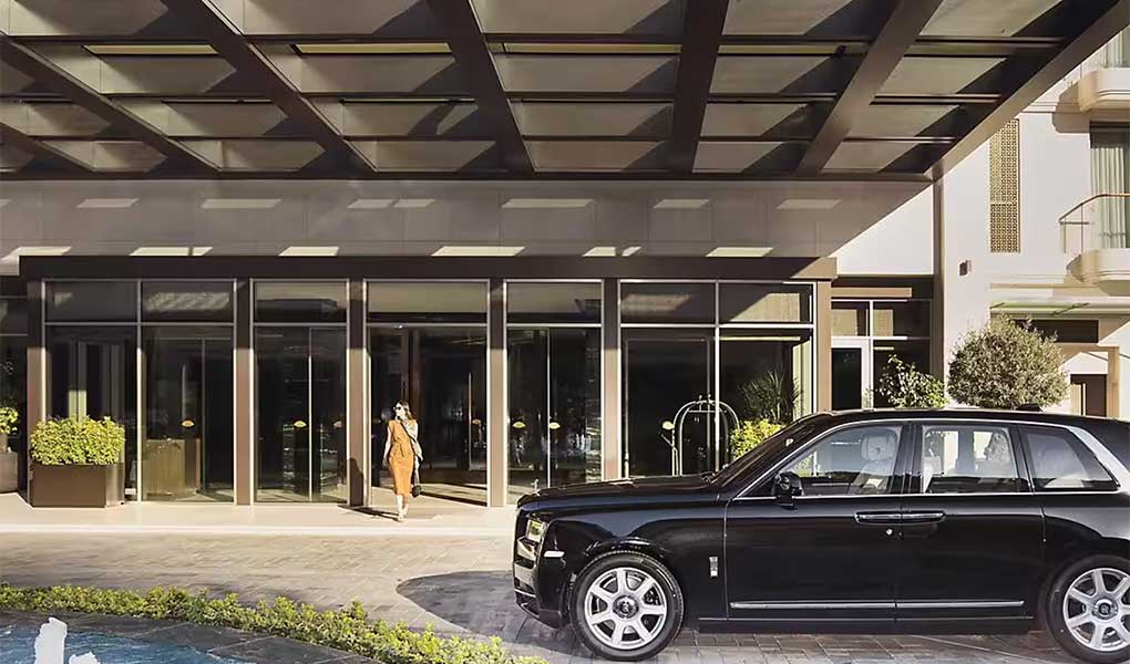 Puerta del entrada del hotel con detalle de coche de lujo