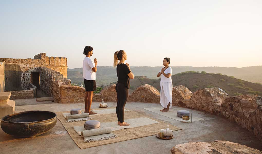 Personas realizando yoga al atardecer balcones Six Senses Fort Barwara