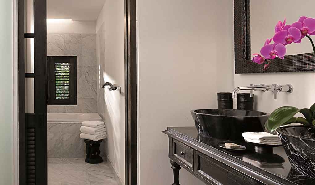 Baño de la habitación del hotel con detalles en madera de teca y mármol