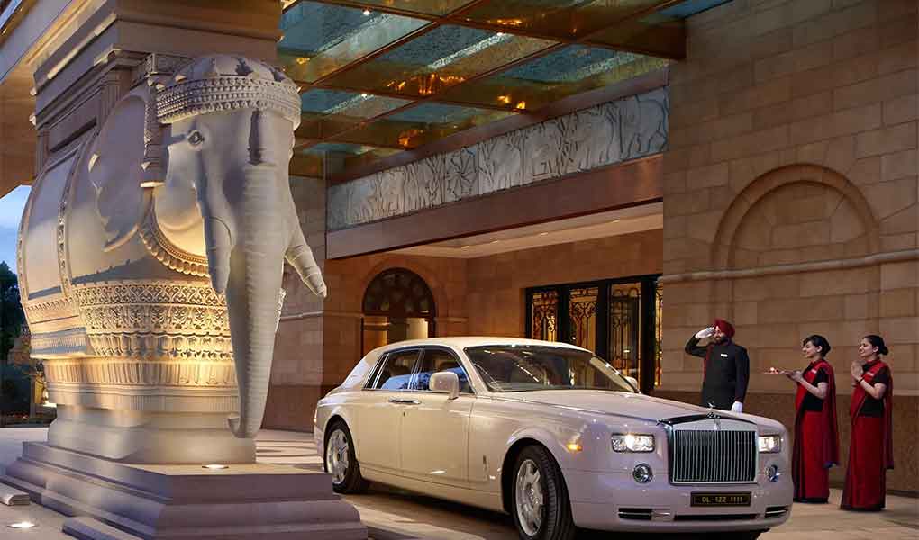 Entrada con coche de lujo en el hotel The Leela Palace New Delhi