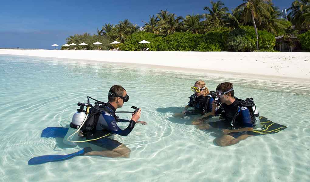Personas en el mar realizando una clase del buceo en el hotel Maldivas