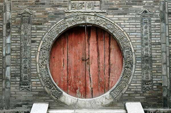 Puerta antigua en madera color rojo en China con paredes en piedra 