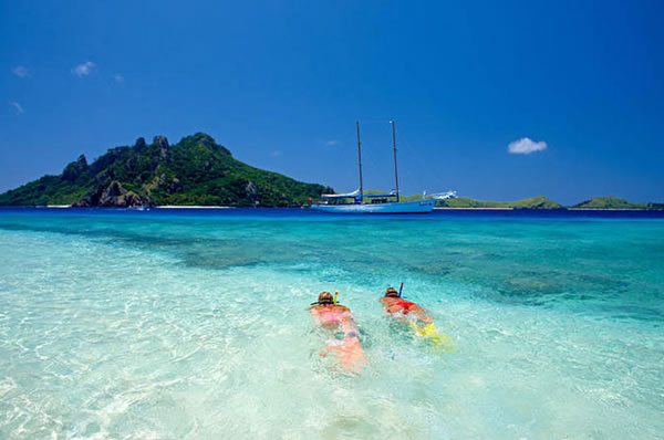 Actividades en Fiji una pareja nadando en la playa de arena blanca