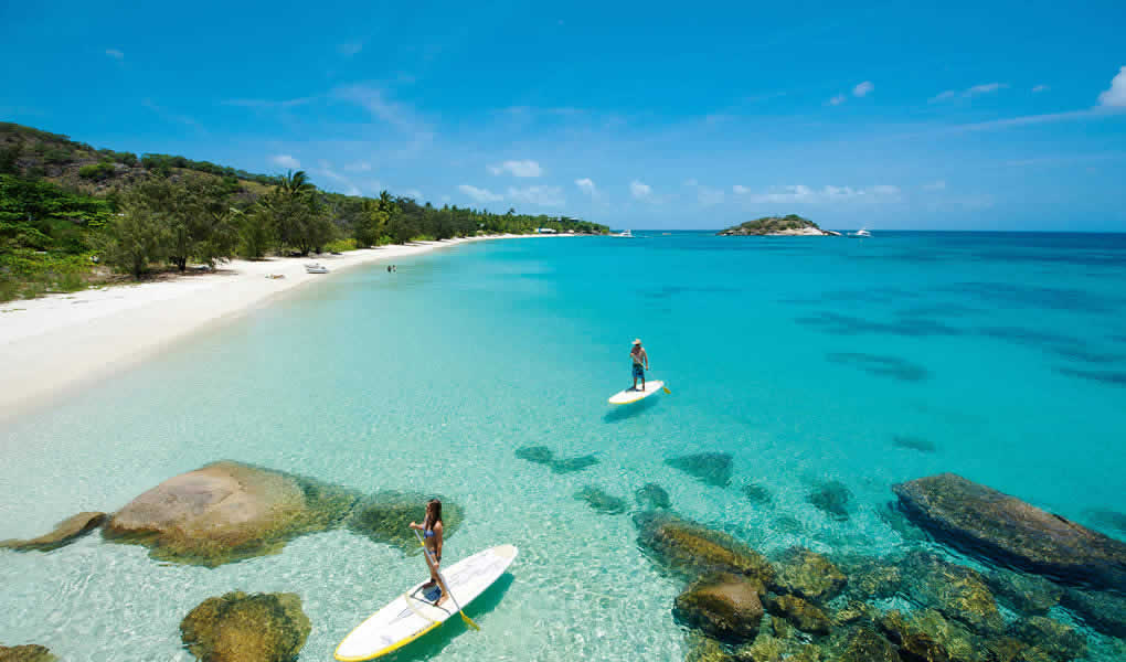 Pareja haciendo stand up paddle barrera de coral Australia. 