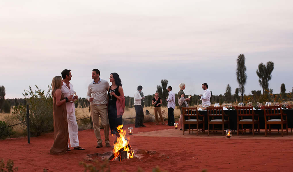 Grupo de personas al atardecer junto al fuego en Longitude 131 Australia