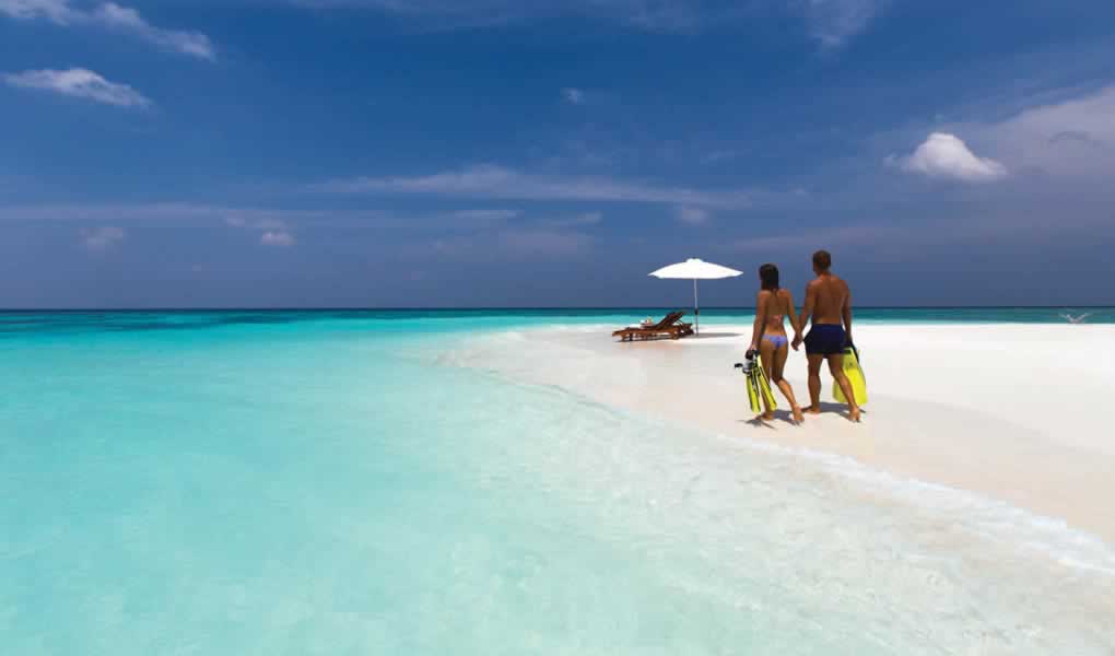 Pareja caminando playa Maldivas en hotel Atmosphere Kanifushi