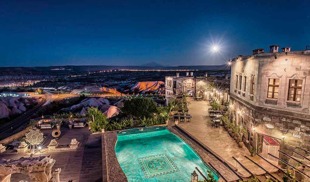 Piscina exterior iluminada con cielo nocturno del hotel Museum Hotel Cappadocia
