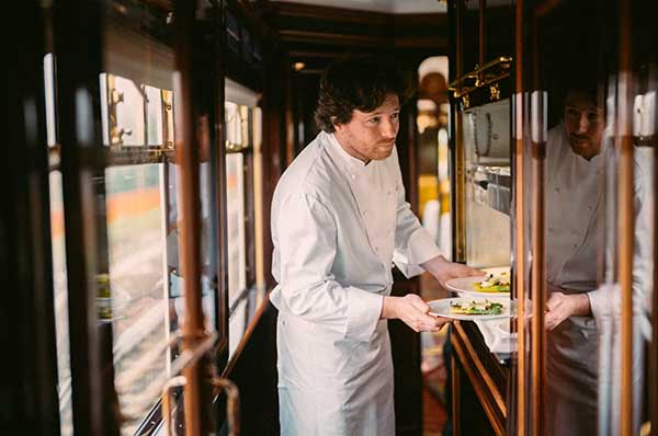 Chef del tren de lujo sirviendo comida camarote