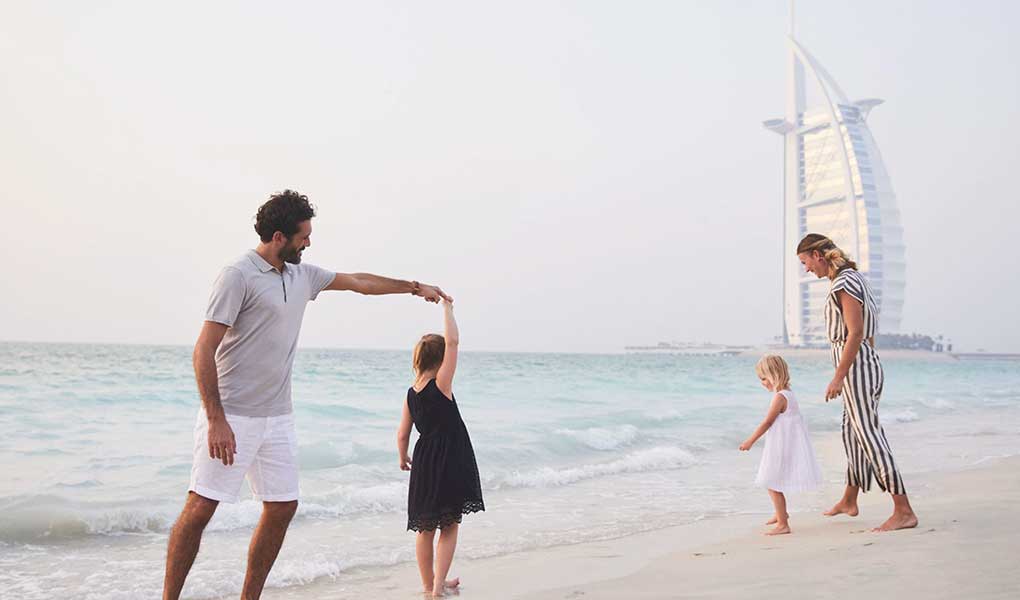Familia jugando en la playa fondo Burj Al arab en Jumeirah Beach