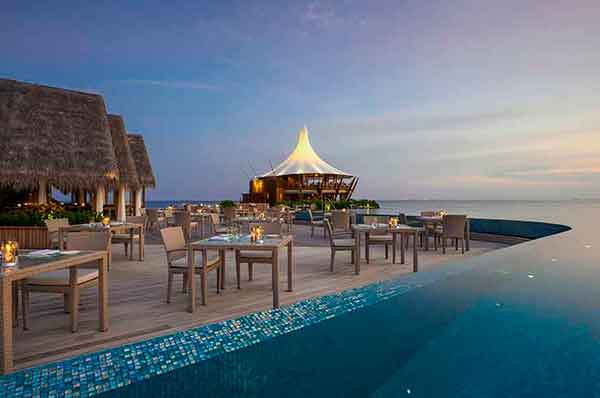 Zonas comunes y piscina exterior del hotel con vistas al horizonte en Maldivas