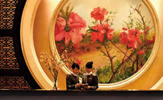 Recepción de un hotel de lujo en Asia, con una imagen de fondo de flores color rojo. 